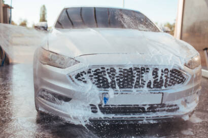 Professional detailer using a machine polisher to remove scratches and swirl marks from a car's paint."