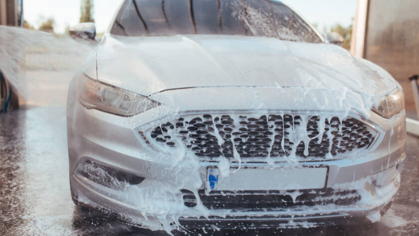 Professional detailer using a machine polisher to remove scratches and swirl marks from a car's paint."