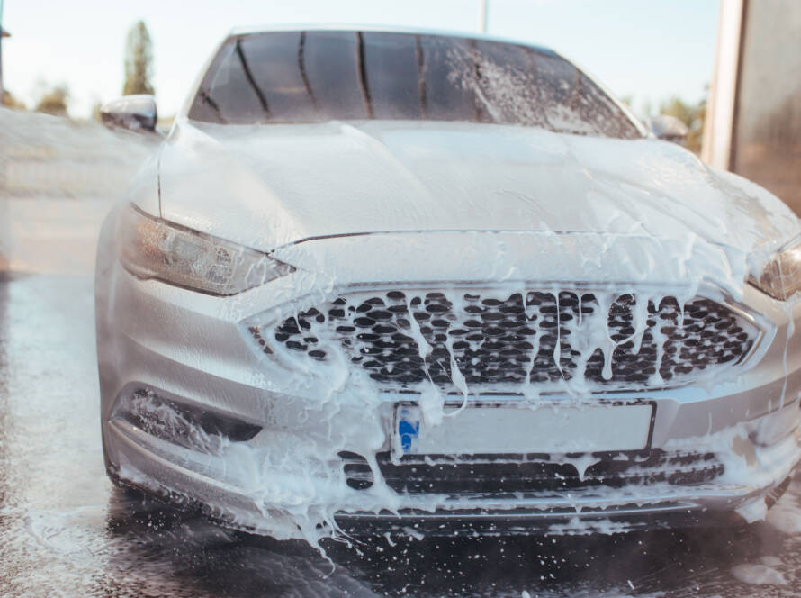 Professional detailer using a machine polisher to remove scratches and swirl marks from a car's paint."