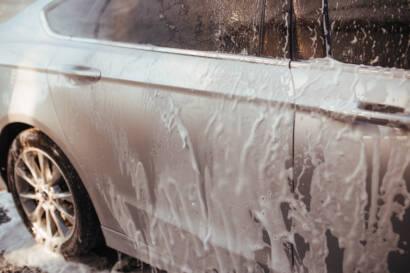 A close-up photo of water beading on a ceramic-coated car hood, showcasing hydrophobic properties.