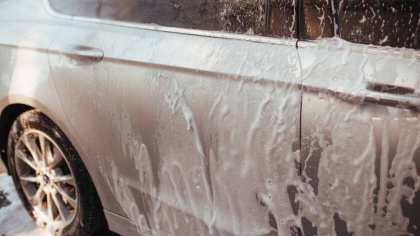 A close-up photo of water beading on a ceramic-coated car hood, showcasing hydrophobic properties.