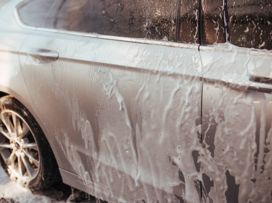 A close-up photo of water beading on a ceramic-coated car hood, showcasing hydrophobic properties.