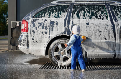 An 85AutoSpa technician detailing a car in a Sandy Springs driveway, showcasing the convenience of mobile service.