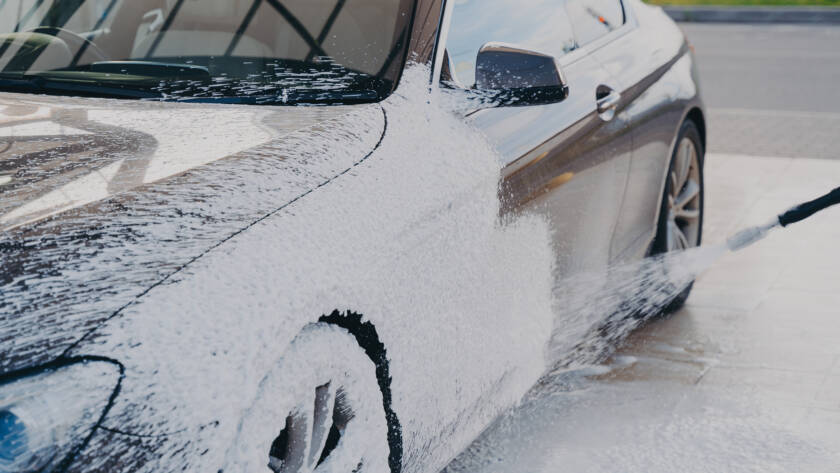 An 85AutoSpa mobile detailing van parked in a Sandy Springs driveway, with technicians cleaning a car.