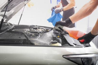 A close-up of water beading on a black car hood after ceramic coating application.