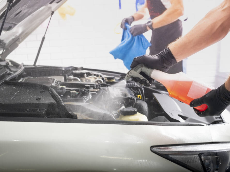 A close-up of water beading on a black car hood after ceramic coating application.