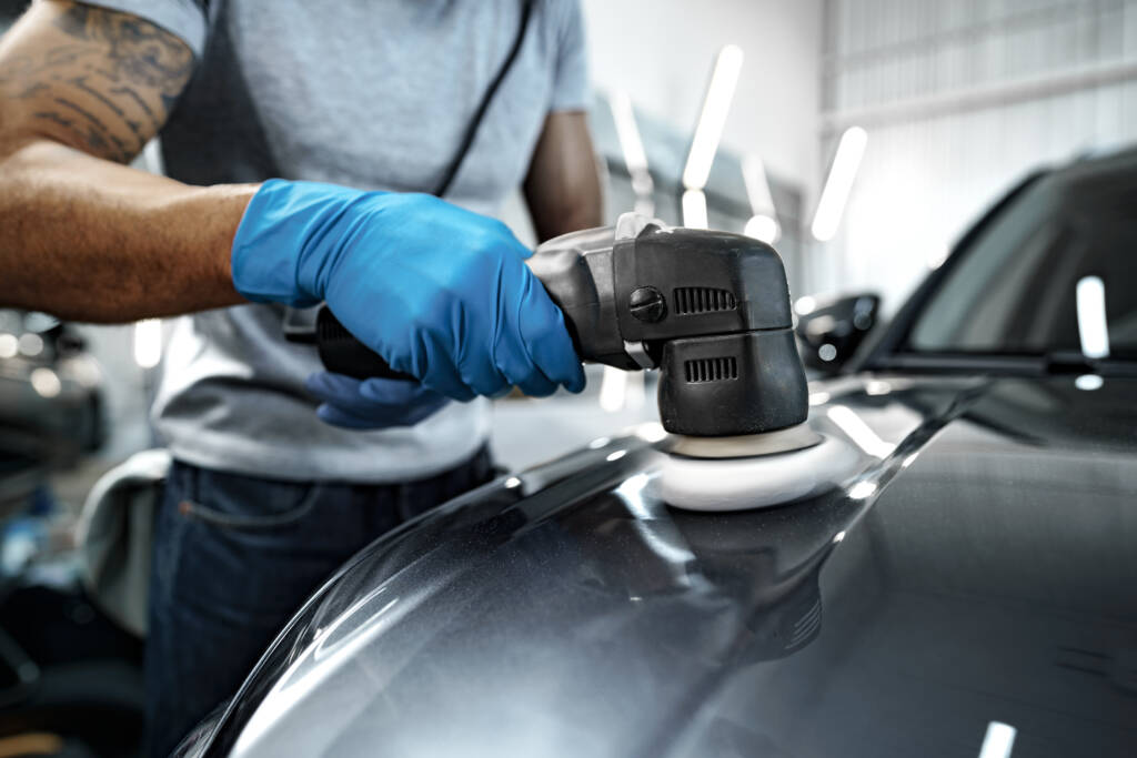 Detailer using a polishing machine to correct paint imperfections on a car.