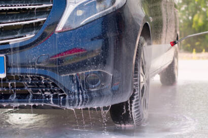 Black car with water beading on ceramic coated hood, showcasing hydrophobic properties."