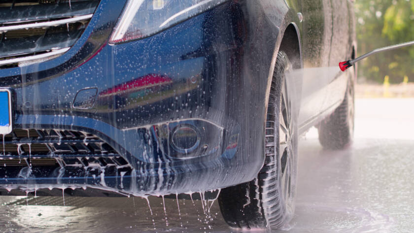 Black car with water beading on ceramic coated hood, showcasing hydrophobic properties."