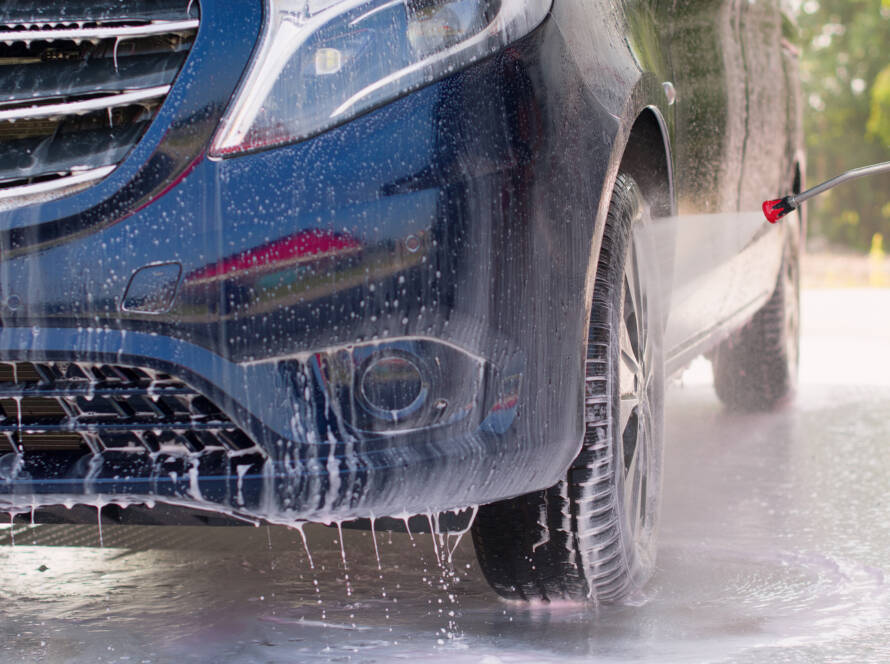 Black car with water beading on ceramic coated hood, showcasing hydrophobic properties."