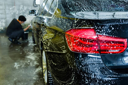 A photo of a detailer applying ceramic coating to a car with a focused expression.