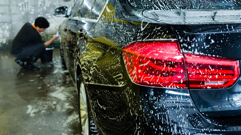 A photo of a detailer applying ceramic coating to a car with a focused expression.