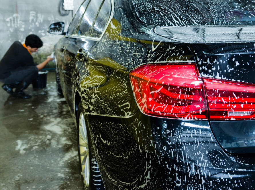 A photo of a detailer applying ceramic coating to a car with a focused expression.