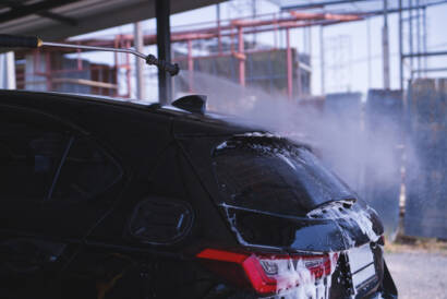 A car parked in a sunny Roswell driveway, showcasing the hydrophobic properties of ceramic coating.