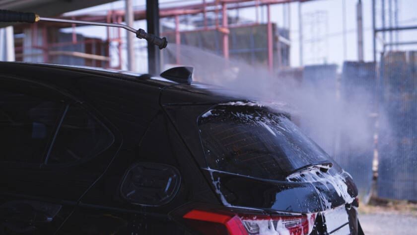 A car parked in a sunny Roswell driveway, showcasing the hydrophobic properties of ceramic coating.