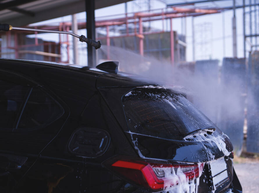 A car parked in a sunny Roswell driveway, showcasing the hydrophobic properties of ceramic coating.