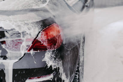 A hand applying car wax to a car's hood, resulting in a mirror-like finish.