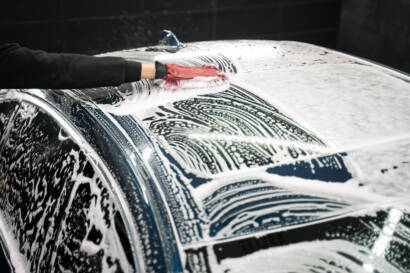 A team of 85AutoSpa detailers posing with a gleaming car.