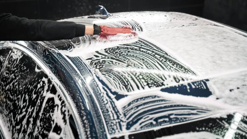 A team of 85AutoSpa detailers posing with a gleaming car.