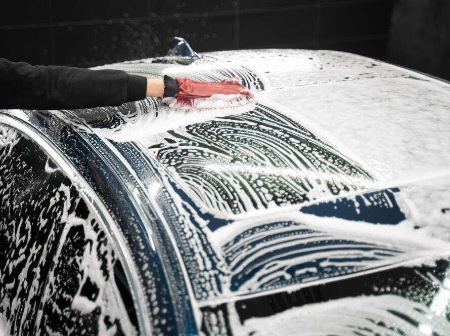 A team of 85AutoSpa detailers posing with a gleaming car.