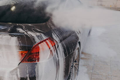 A smiling 85AutoSpa detailer carefully hand-washing a car.