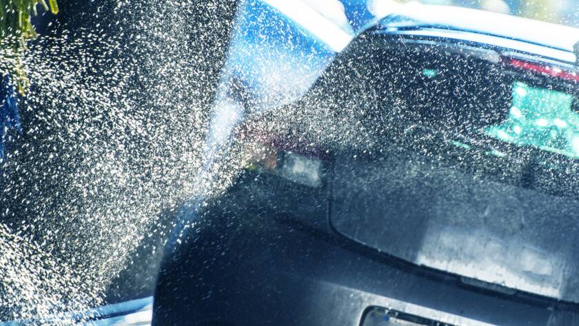 A clear, transparent film being applied to a car's front bumper.