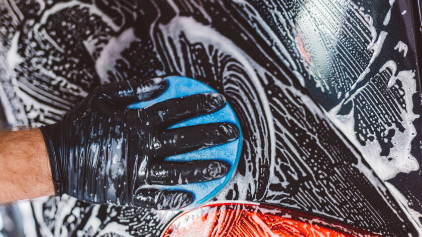 A close-up photo of a water beading on a ceramic-coated car panel, showcasing its hydrophobic properties.