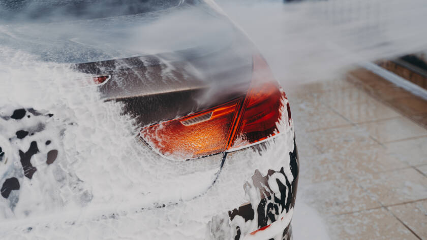 A close-up image of water beading on a ceramic-coated car hood, showcasing its hydrophobic properties.