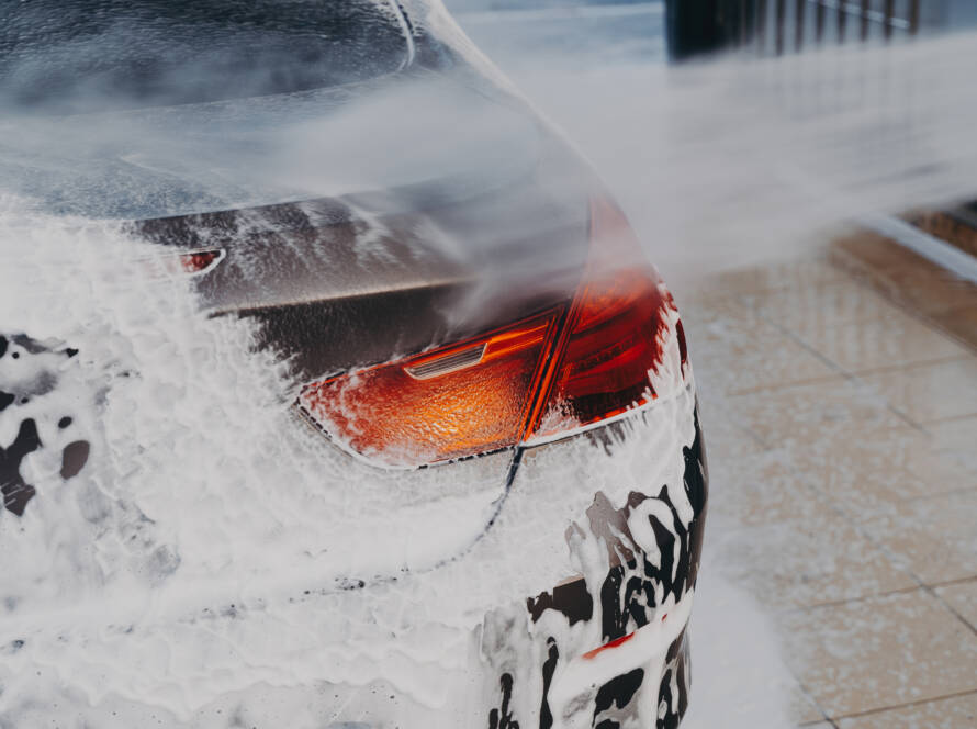 A close-up image of water beading on a ceramic-coated car hood, showcasing its hydrophobic properties.